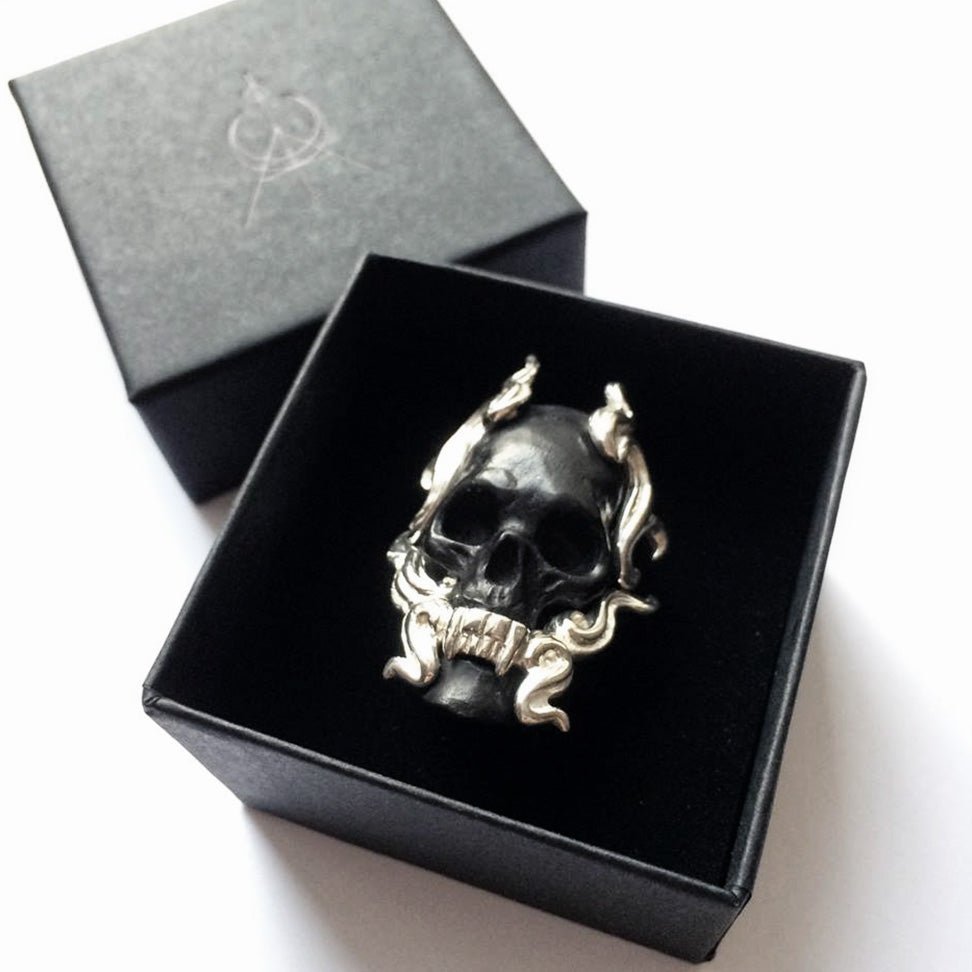 Black Mayla Skull ring in a black jewelry box on a white surface