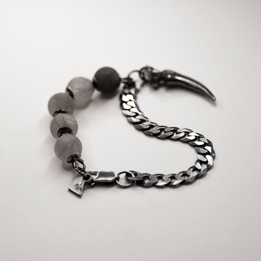 Claw Bracelet placed on a white surface, focus on a lobster clasp between chain and beaded part.