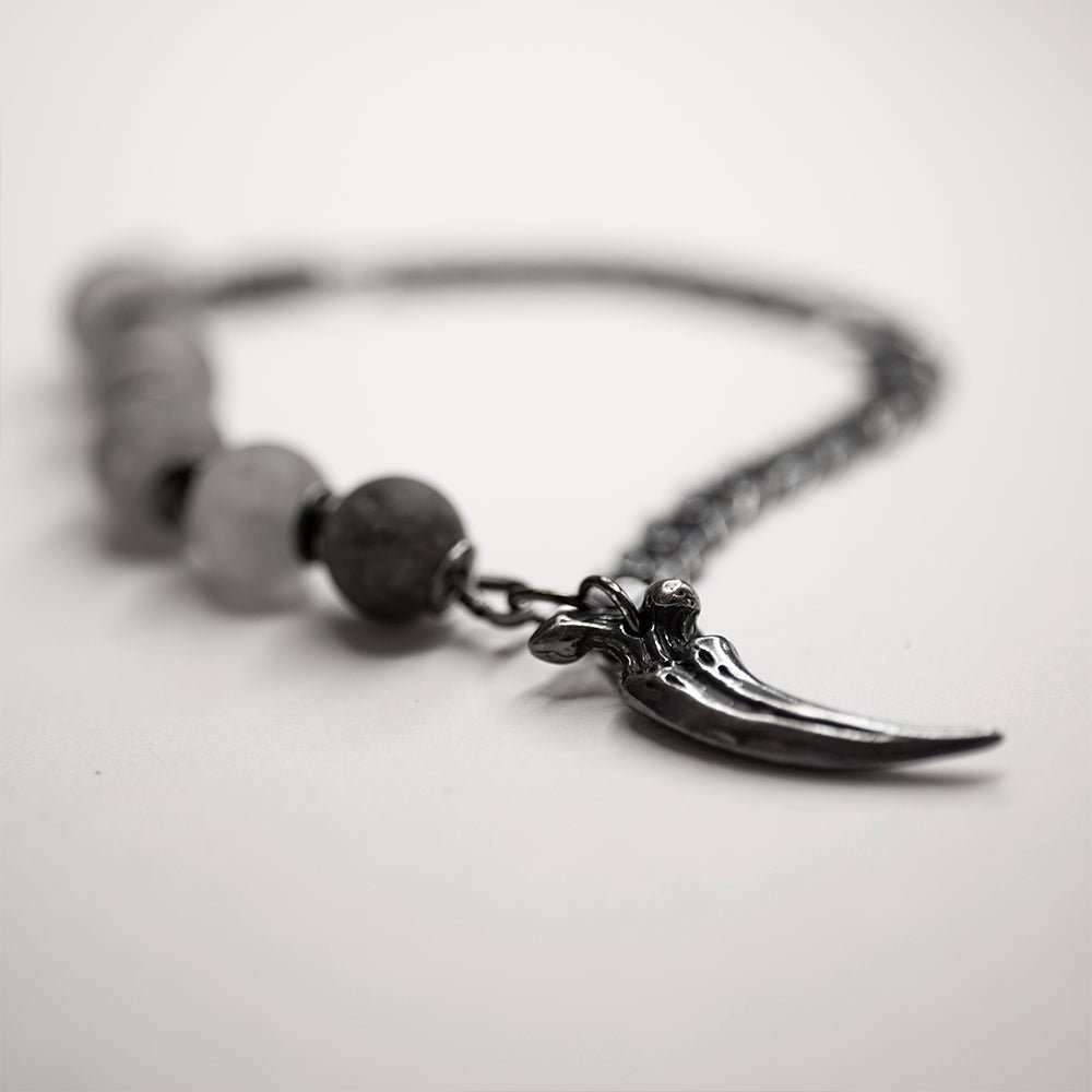 Claw Bracelet placed on a white surface - focus on a claw charm, the rest of the bracelet is blurry