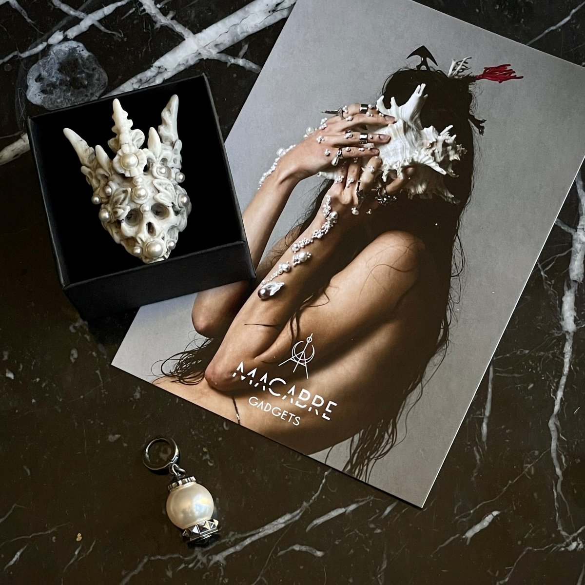 Coral Crown Skull ring in jewelry box — marble skull ring with coral pearl crown on black marble surface | Macabre Gadgets