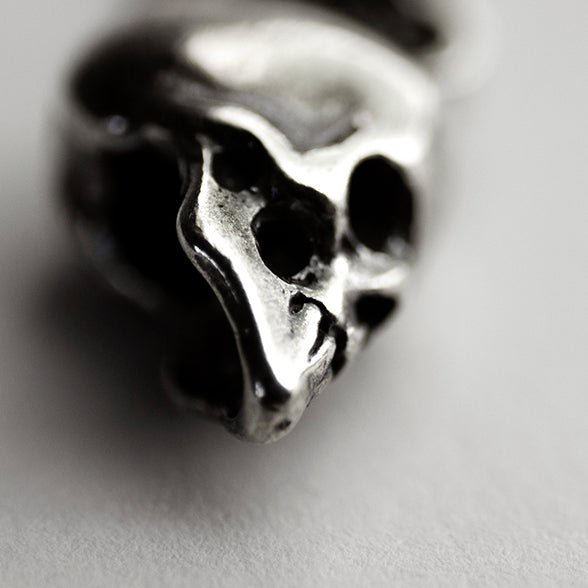 Silver Skull earring - close-up of miniature skull showing sculpted details on neutral background