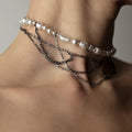 A close-up of a person wearing the Dew necklace - combination of silver pearls and black chains.