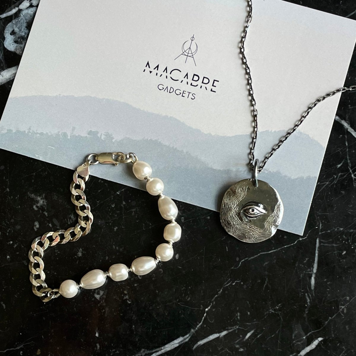 Double bracelet and Oculus pendant placed on a black marble surface