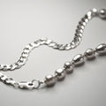 Double necklace - close-up of hand knotted pearls strand with silver flat curb chain on white surface