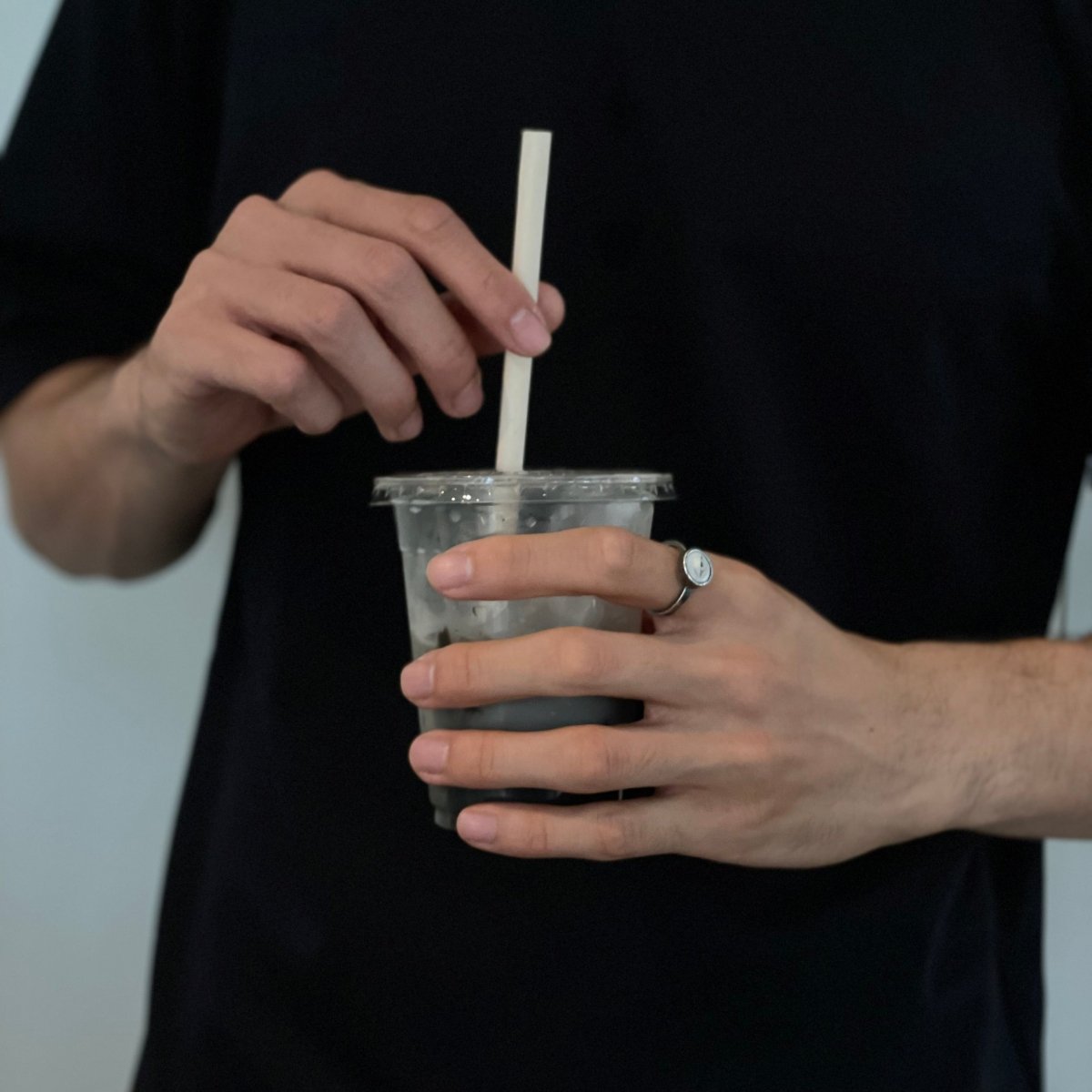 Eye ring on a man's hand holding an iced coffee