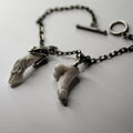 Faun Bracelet lying on the white surface, both charms and holders are visible, toggle clasp is blurry, but still visible