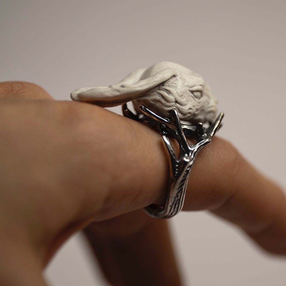 Hare ring - white variant - on a model's hand, focus on dark silver twigs, holding an eerie white hare's head