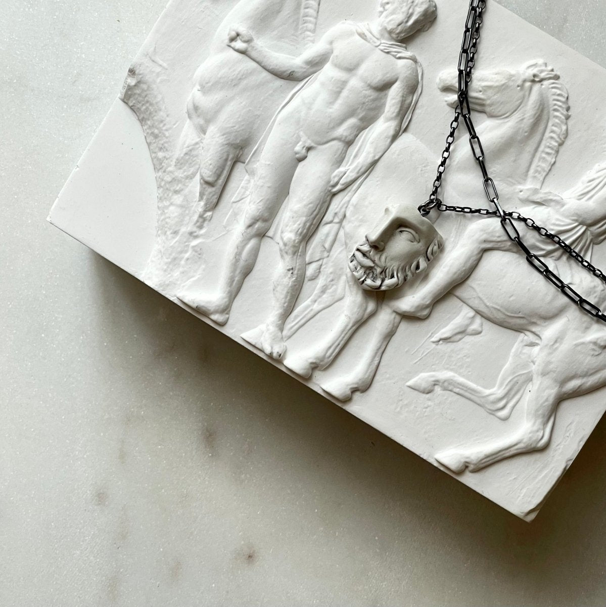 Heracles pendant placed on a gypsum tile with low relief
