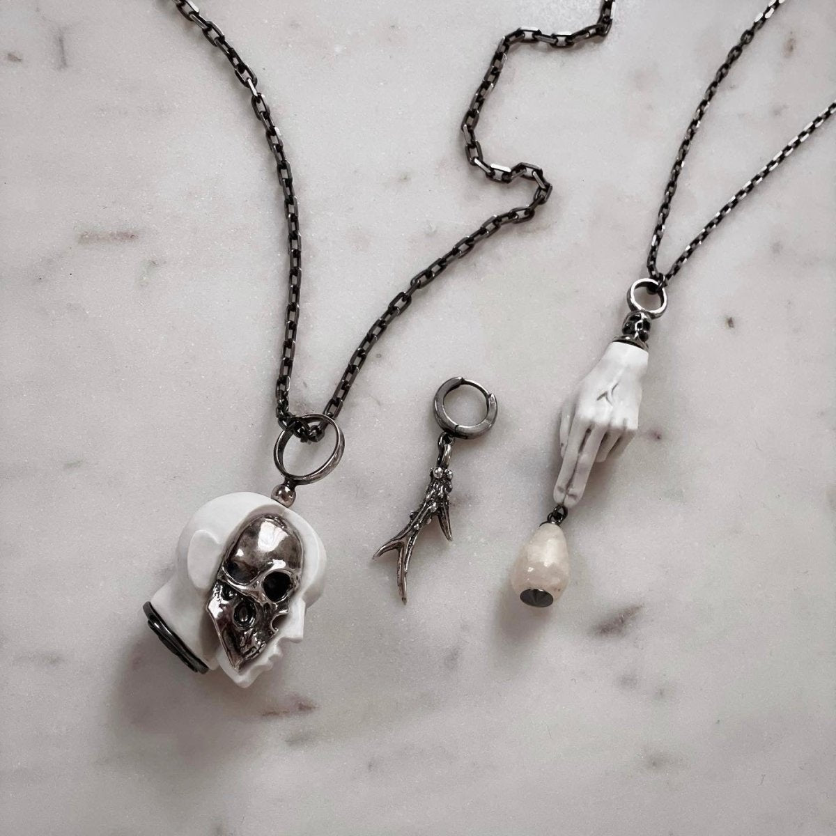 Horn earring along with other jewelry by Macabre Gadgets on white marble surface