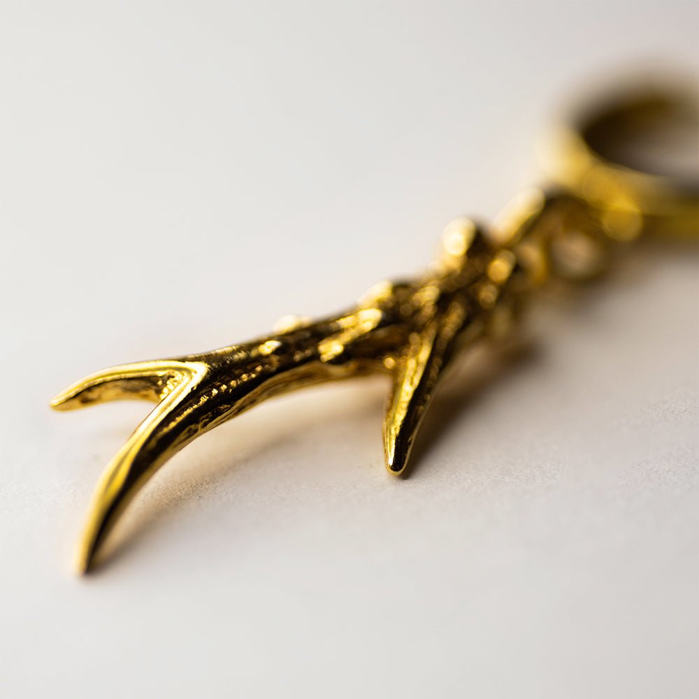 Horn earring - gold-plated horn dangle detail on neutral surface