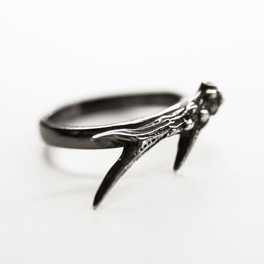 Horn ring on its side, on a white background, showing details and texture of the realistic horn and smooth surface of the band