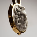 Close-up of  detailed Medusa Shield pendant, intricately carved in bonded marble in 24K gold plated holder with studs highlighting her features.
