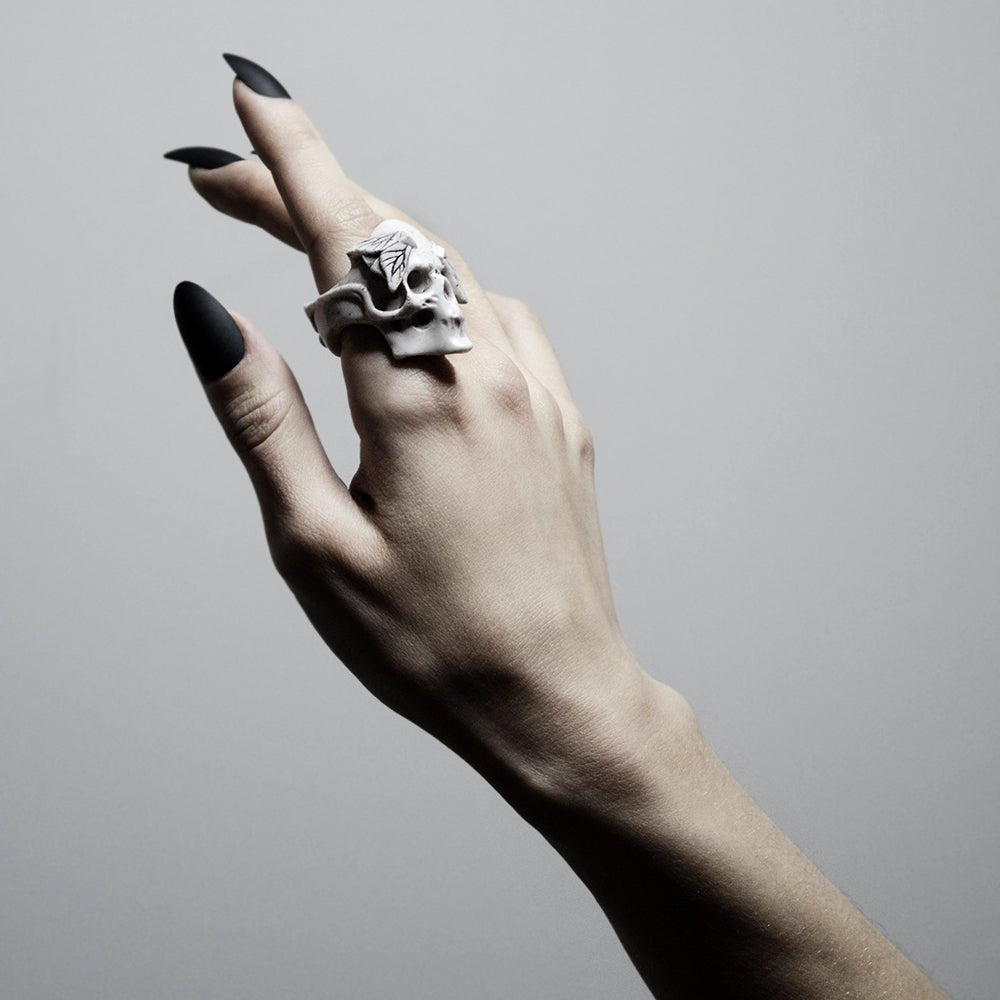 Moths Skull ring worn on a woman's hand with long black nails