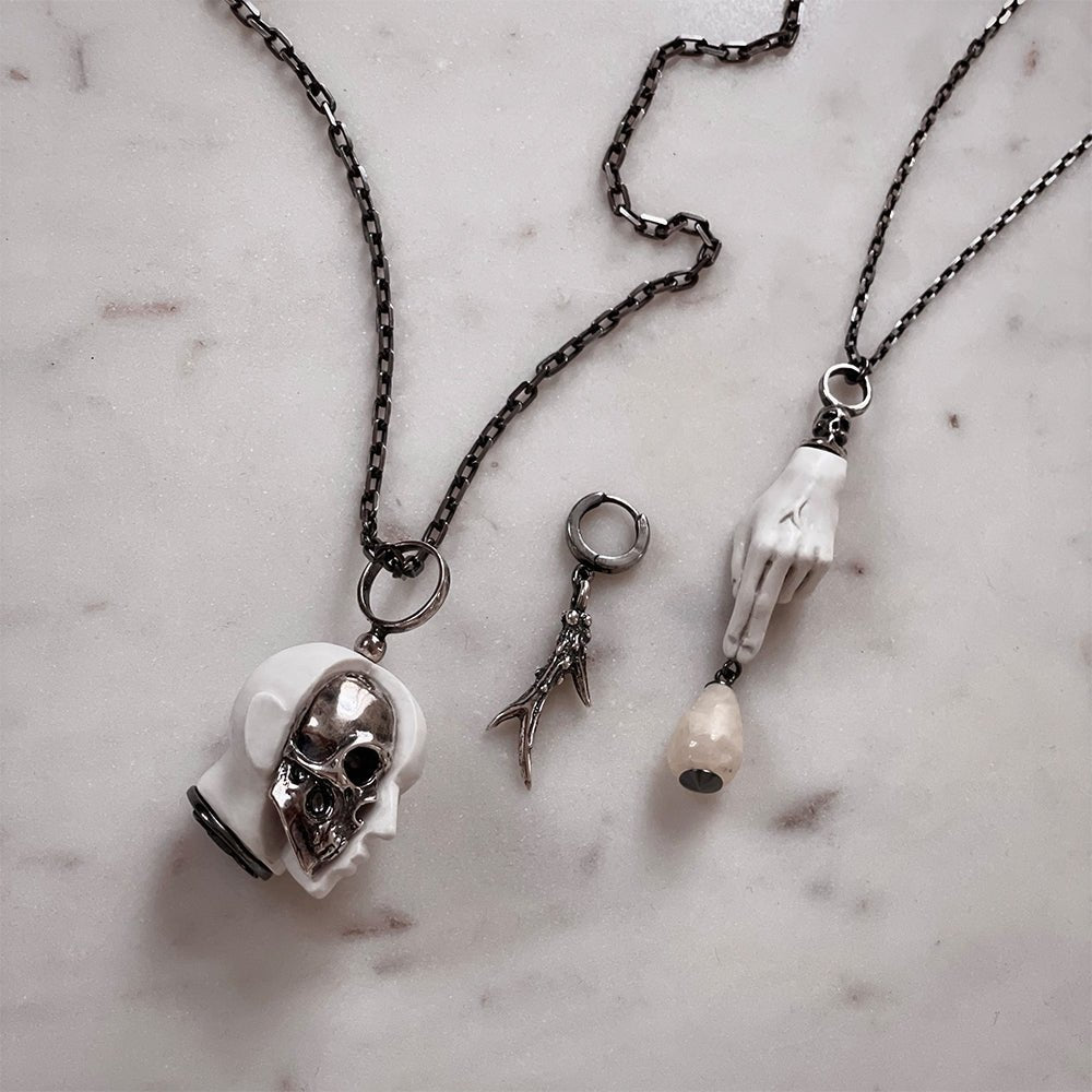 Oracle Skull pendant and other jewelry by Macabre Gadgets on white marble surface