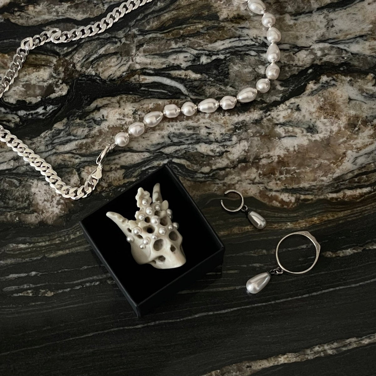 Pearl Crown Skull ring in jewelry box alongside Double necklace — bonded marble and pearl jewelry on marble surface | Macabre Gadgets