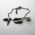 Shell Bracelet placed on a white surface, clear product picture with baroque pearl and seashell charms visible