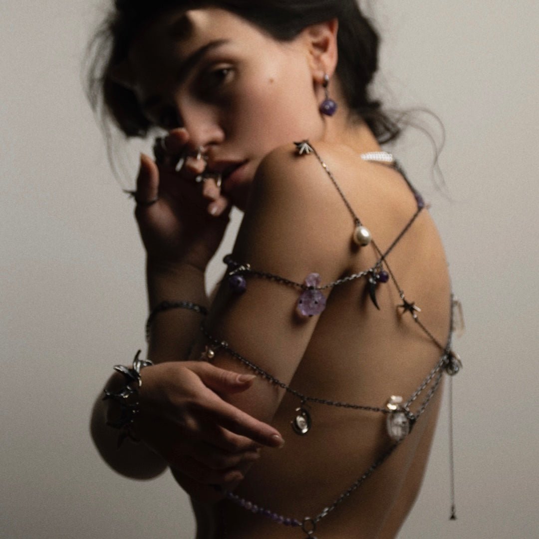 Female model wearing Thistle Amethyst earring along with other chains and layered necklaces by Macabre Gadgets for "Faun" campaign