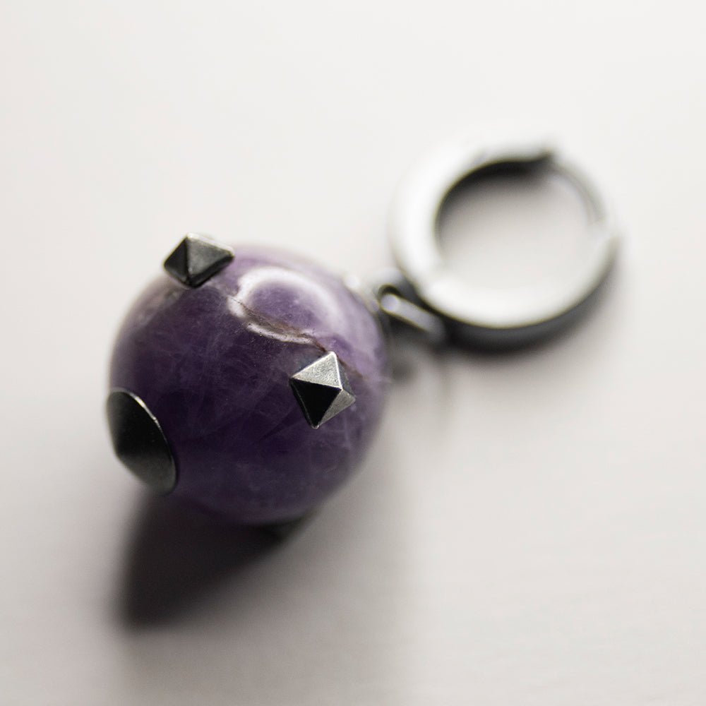 Thistle Amethyst earring - natural stone bead inlayed with silver studs fixed on a hoop clasp placed on white surface