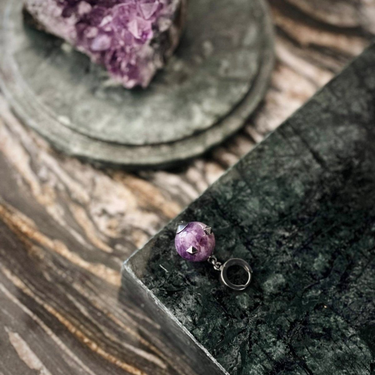 Thistle Amethyst earring - amethyst hoop earring placed on green marble surface along with raw amethyst crystals
